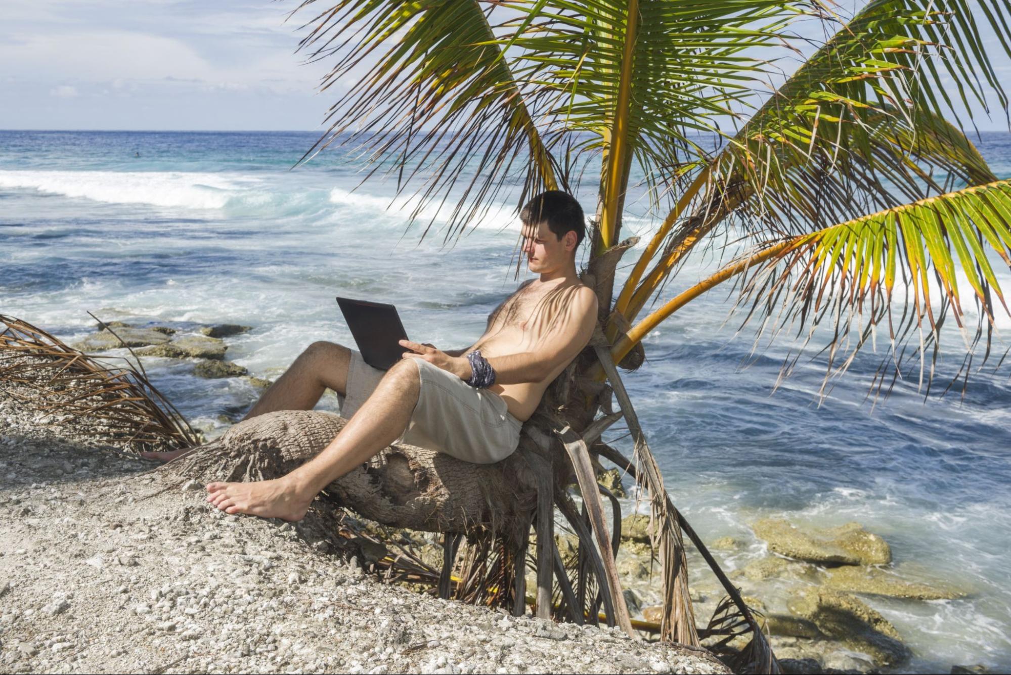 Man sitting with laptop on the beach