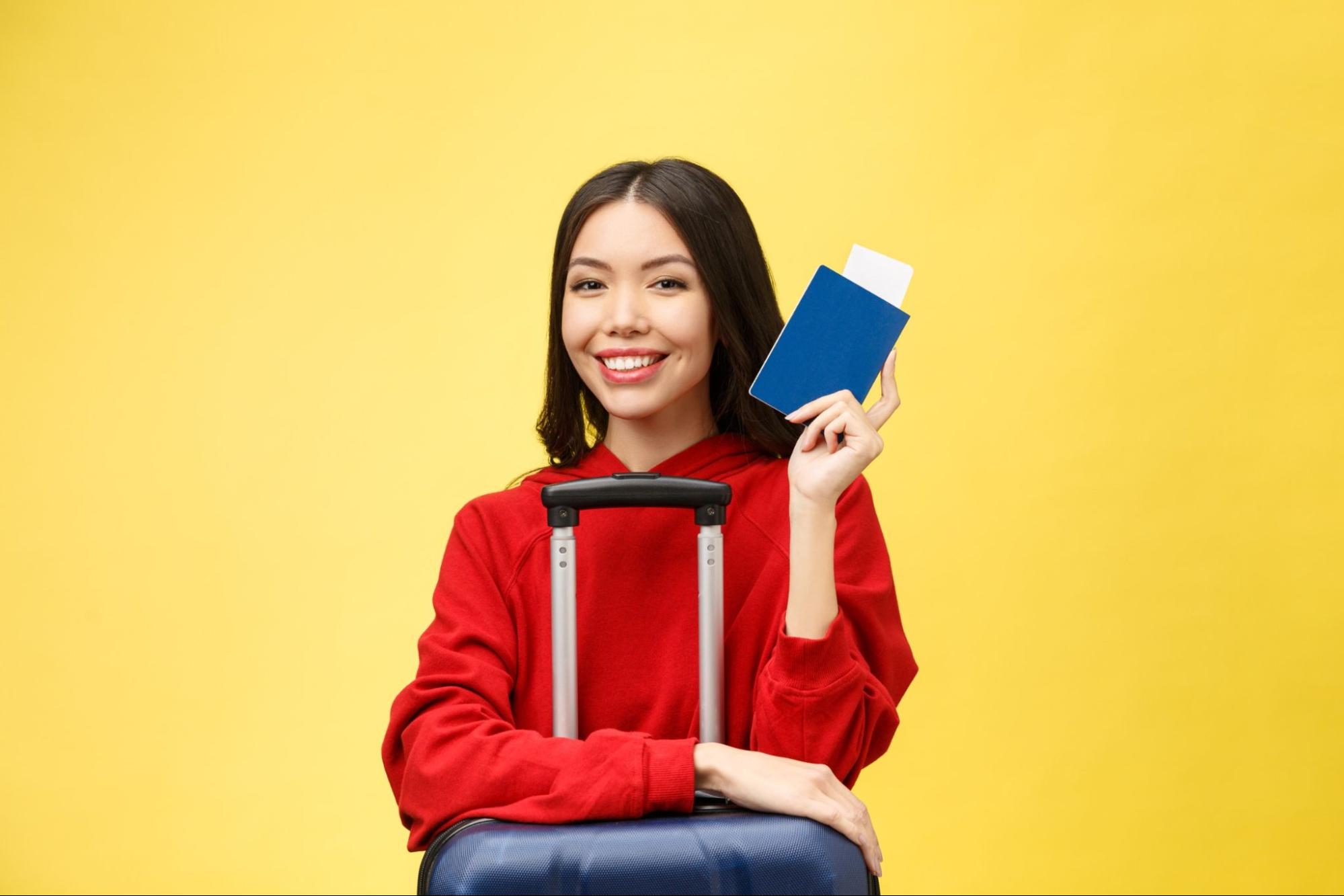 Young beautiful asian woman traveler with passport and suitcase
